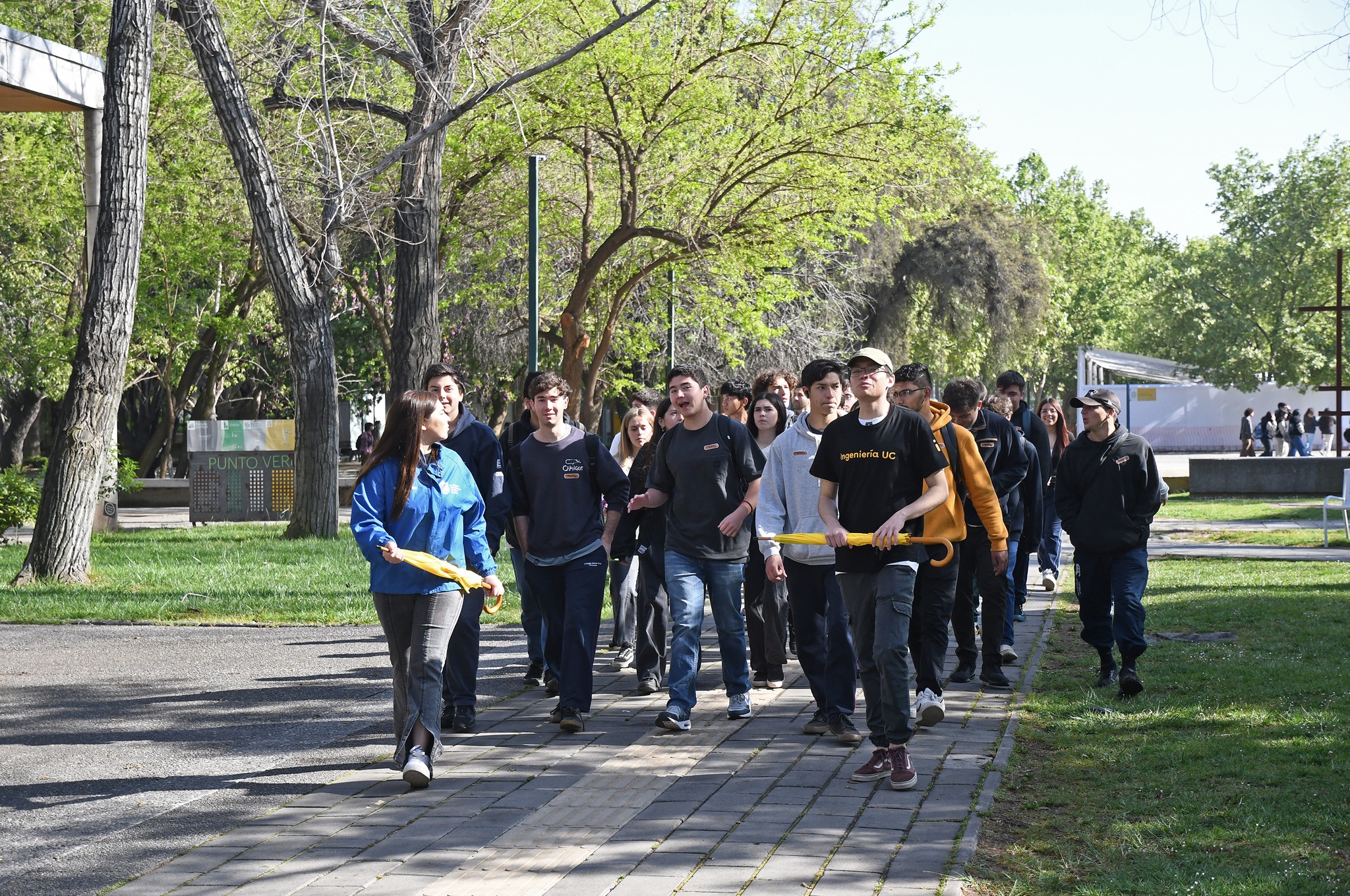 Grupo de estudiantes de enseñanza media caminando por el campus, guiados por una embajadora UC